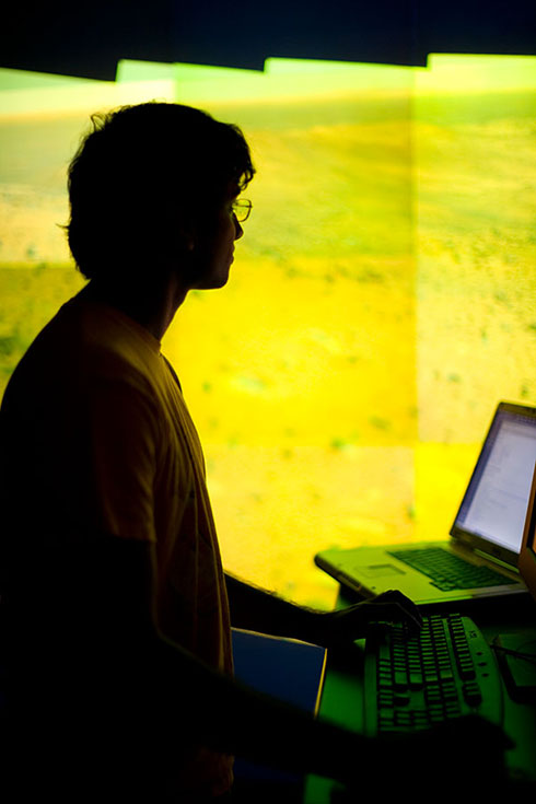 silhouette of young man standing at a computer keyboard